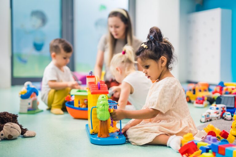 Kinderen en een leidster spelen met kleurrijk speelgoed op de kinderopvanglocatie