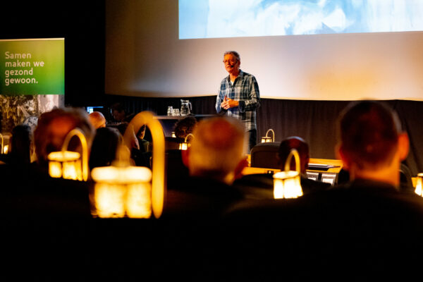 Gijs Wanders geeft op het podium een presentatie op het congres over dementie