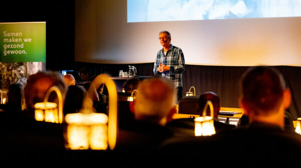 Gijs Wanders geeft op het podium een presentatie op het congres over dementie