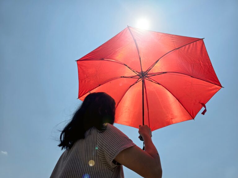 Vrouw houdt oranje parasol boven haar hoofd.
